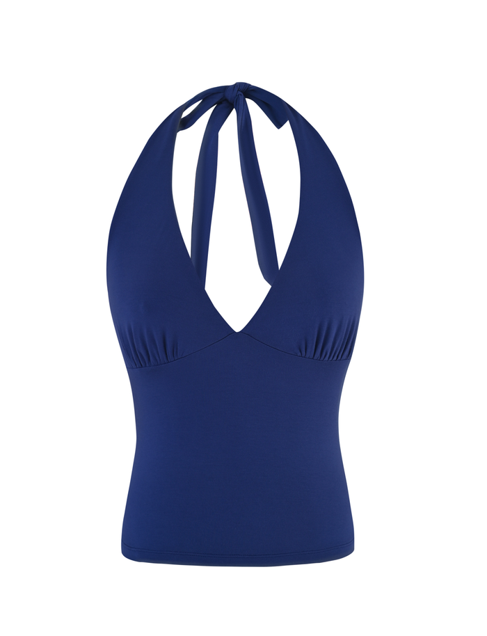 The MERIAL TOP by TIGERMIST is a sleeveless denim blue jersey halter with a plunging V-neckline, neck tie closure, and smooth, stretchy fabric that fits snugly at the waist.