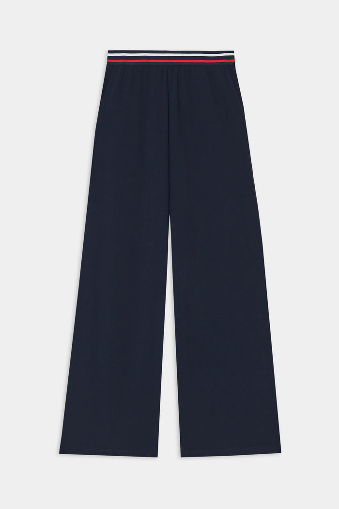 The SPLITS59 Michele Airweight Trouser in indigo features wide legs and an elastic waistband with red, white, and blue stripe detail, shown flat on a white background.