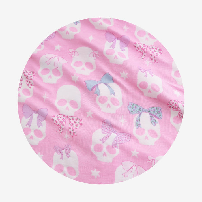 Close-up of the Posh Peanut Ms. Kelly fabric swatch, pink with white skull print, circle crop
