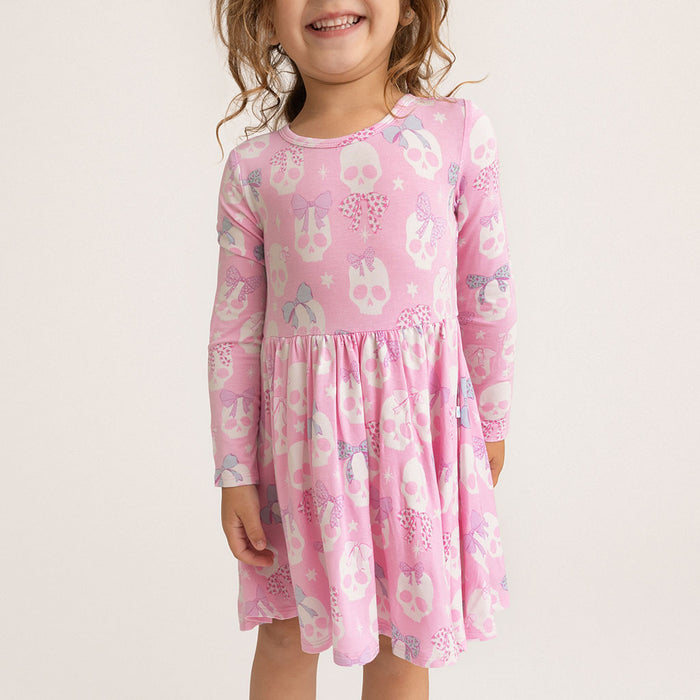Child wearing the Posh Peanut Ms. Kelly Bow Back Twirl Dress, standing at an angle, white background