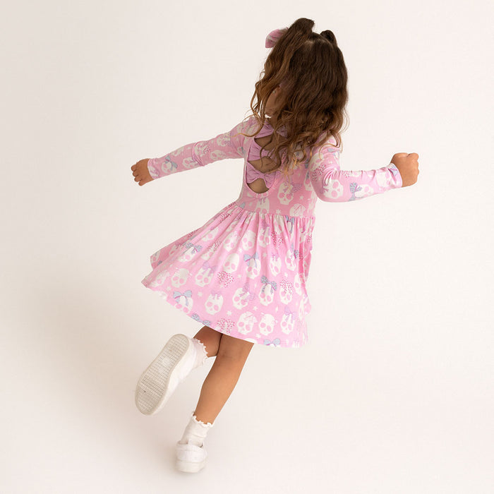 Child twirling in the Posh Peanut Ms. Kelly Bow Back Twirl Dress, skirt flared out, white background