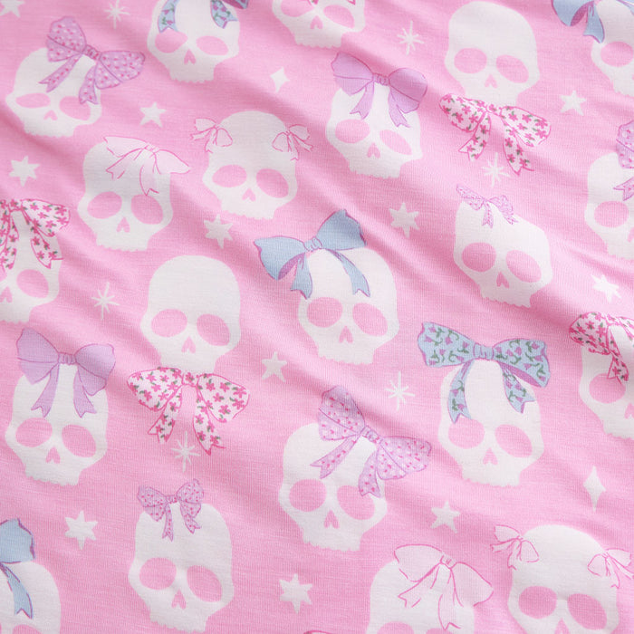 Close-up of the Posh Peanut Ms. Kelly fabric swatch, pink with white skull print, square crop