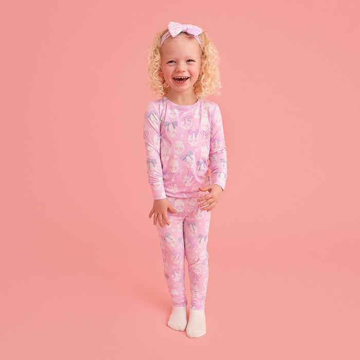 Child standing, wearing the Posh Peanut Ms. Kelly Classic Pajama Set, pink background