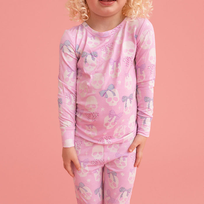 Child standing, wearing the Posh Peanut Ms. Kelly Classic Pajama Set, close-up, pink background