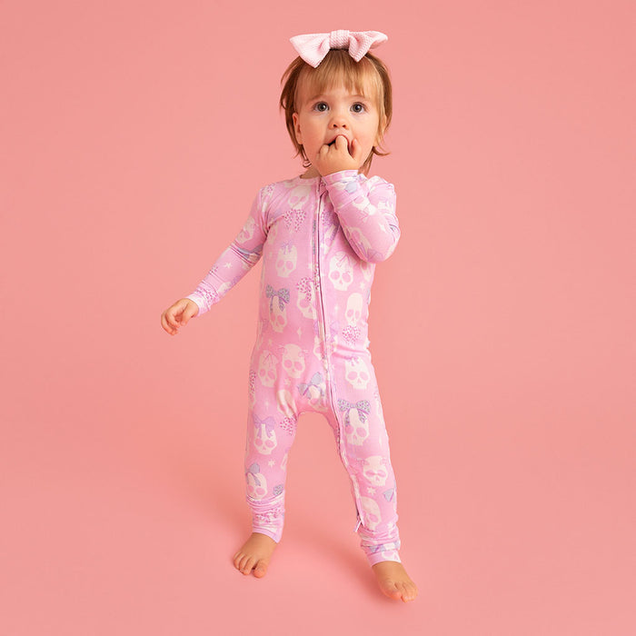 Child standing, wearing the Posh Peanut Ms. Kelly Convertible One Piece, pink background