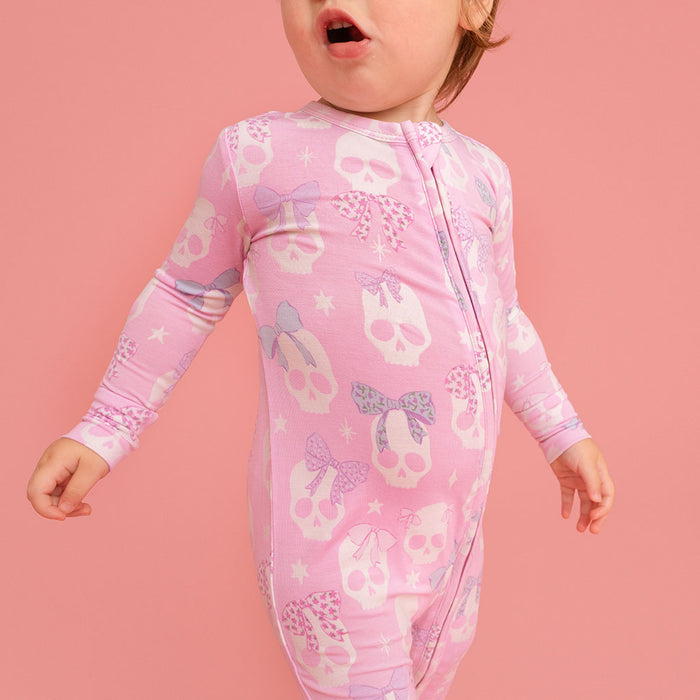 Child standing, wearing the Posh Peanut Ms. Kelly Convertible One Piece, pink background