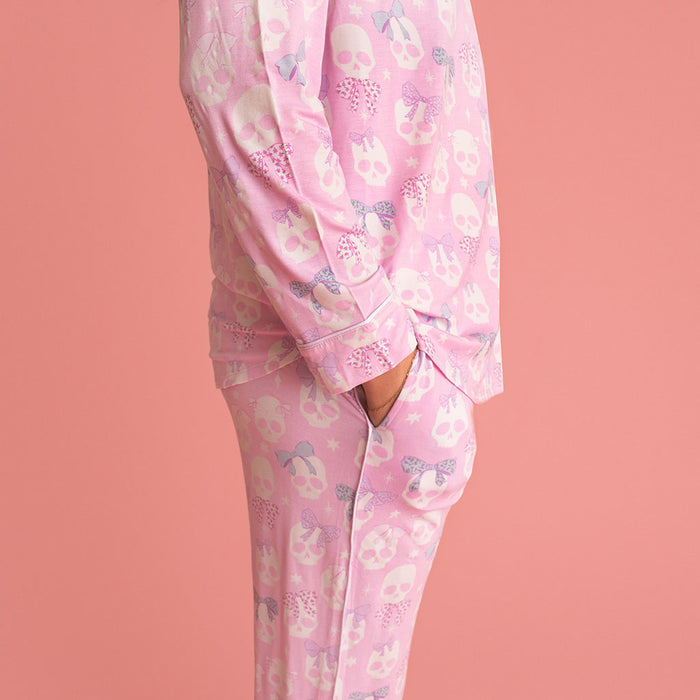 Woman standing at an angle, wearing the Posh Peanut Ms. Kelly Women's Luxe Pajama Pant Set, coral background