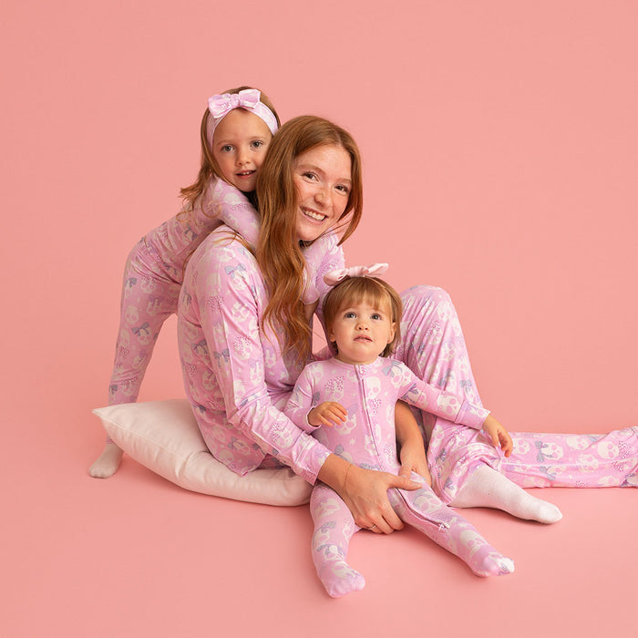 Woman and two children wearing matching Posh Peanut Ms. Kelly pajamas, coral background