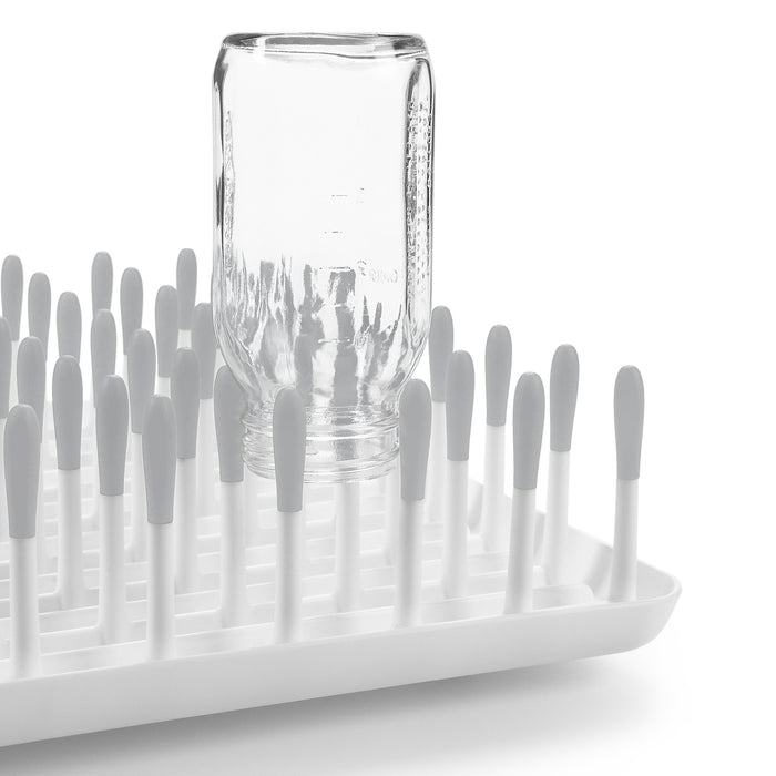 White drying rack with gray pegs and a glass jar for Oxo Tot Bottle & Cup Cleaning Set