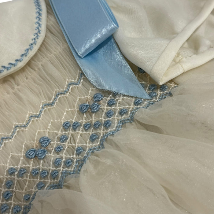 Close-up of intricate light blue handsmocking on Ricardo Ivory Romper