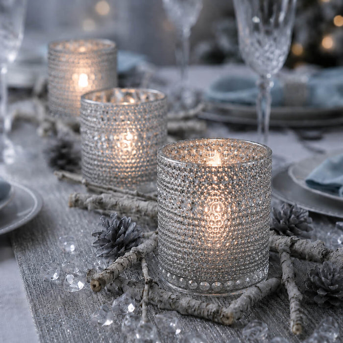 Pearly silver candle holders glowing on a winter-themed table with rustic decor