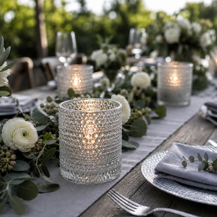 Pearly silver candle holders glowing on an elegant outdoor table with white flowers