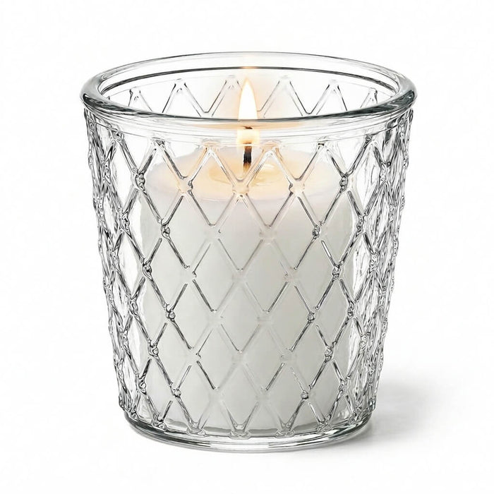 Close-up of a lit candle glowing through a patterned clear glass Tipper Vase & Candle Holder