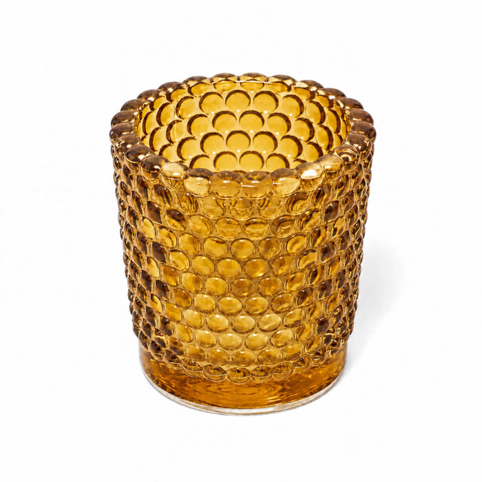 Amber hobnail glass votive candle holder on white background