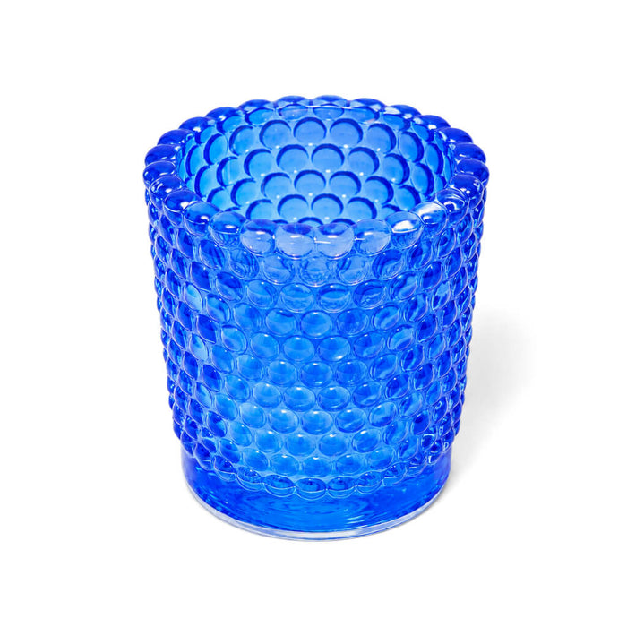 Blue hobnail glass votive candle holder standing on white background