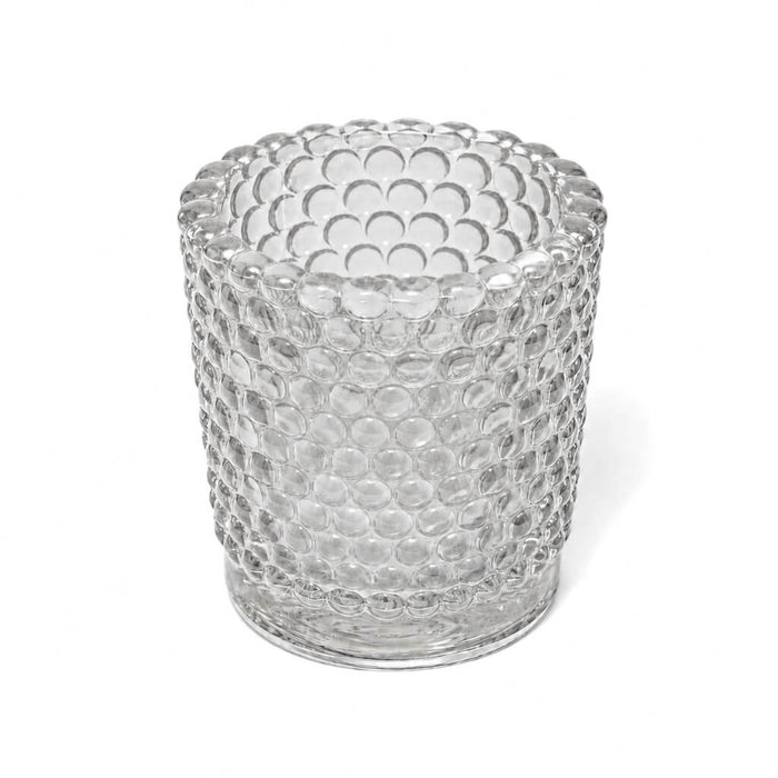An empty clear hobnail glass votive holder isolated on a solid white background