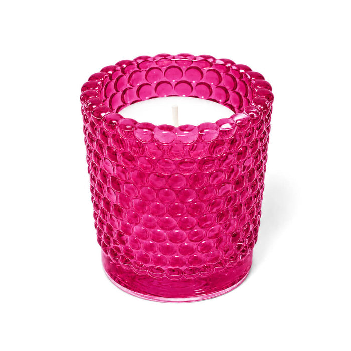 Pink hobnail glass votive holder with white candle on white background