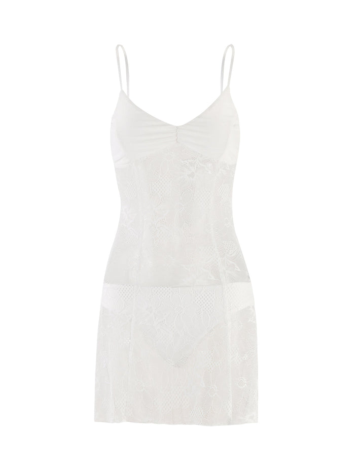 The SASKIA DRESS - WHITE from TIGERMIST is a white lace slip dress with thin spaghetti straps. This elegant piece features a fitted bodice and slight gathering at the bust, showcasing an intricate lace pattern throughout. It falls gracefully to mid-thigh length.