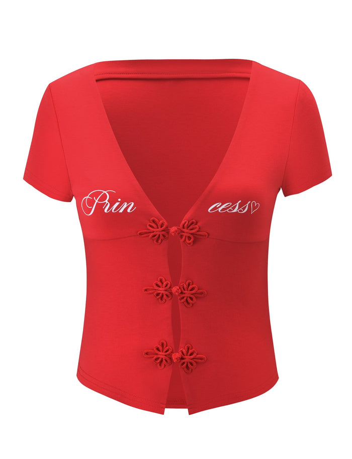 The SAVINA TOP - RED by TIGERMIST is a short-sleeve, V-neck top with embroidered button details and a white cursive "Princess" graphic with a heart across the chest.
