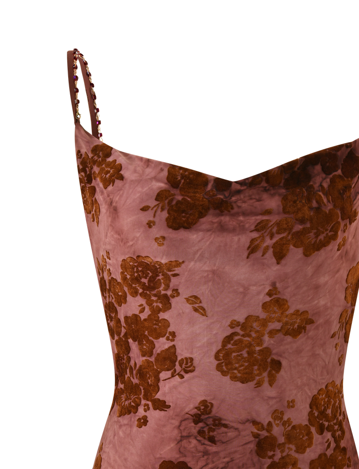 A close-up of the TIGERMIST SPARROW MINI DRESS - CHOCOLATE BURNOUT, showing thin straps and a pinkish-mauve base with brown floral burnout patterns. The strap features delicate decorative details.