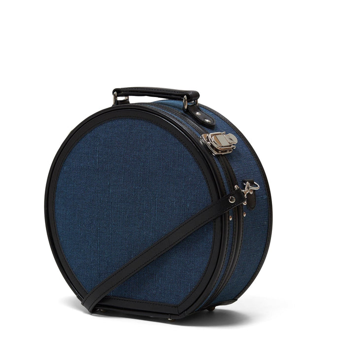 Angled product view of the small hatbox Editor linen suitcase with navy body, black trims and shoulder attachment strap