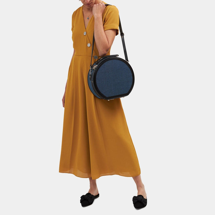 Model with the small hatbox Editor linen suitcase with navy body,  black trims and shoulder attachment strap