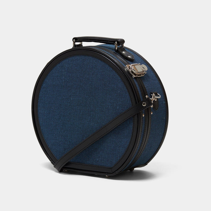 Angled product view of the small hatbox Editor linen suitcase with navy body, black trims and shoulder attachment strap