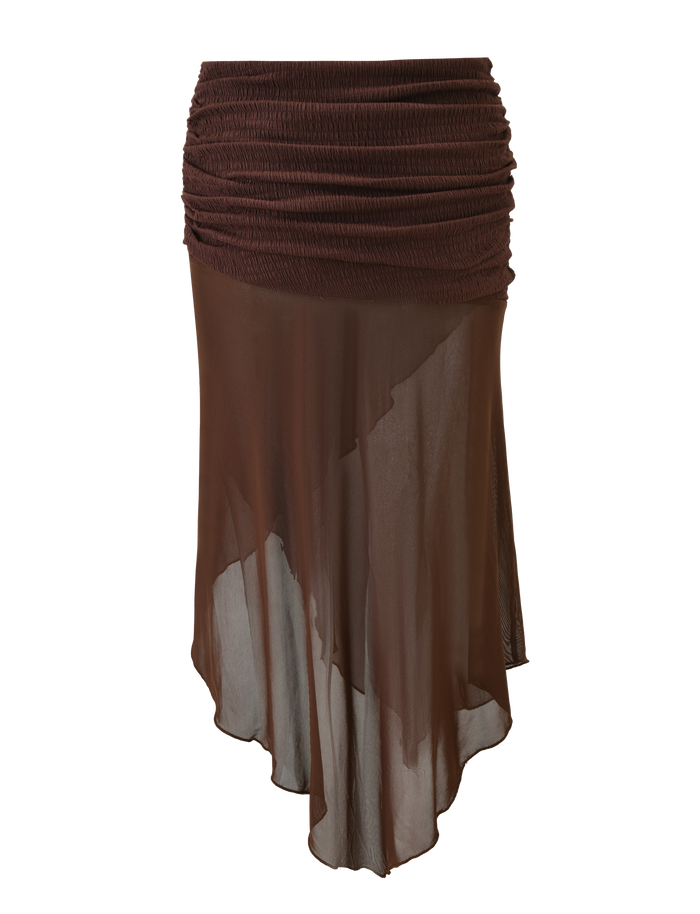 The TIGERMIST ZINNIA MIDI SKIRT in chocolate features a textured stretch knit waistband and a sheer, asymmetrical hem for a layered, airy look.